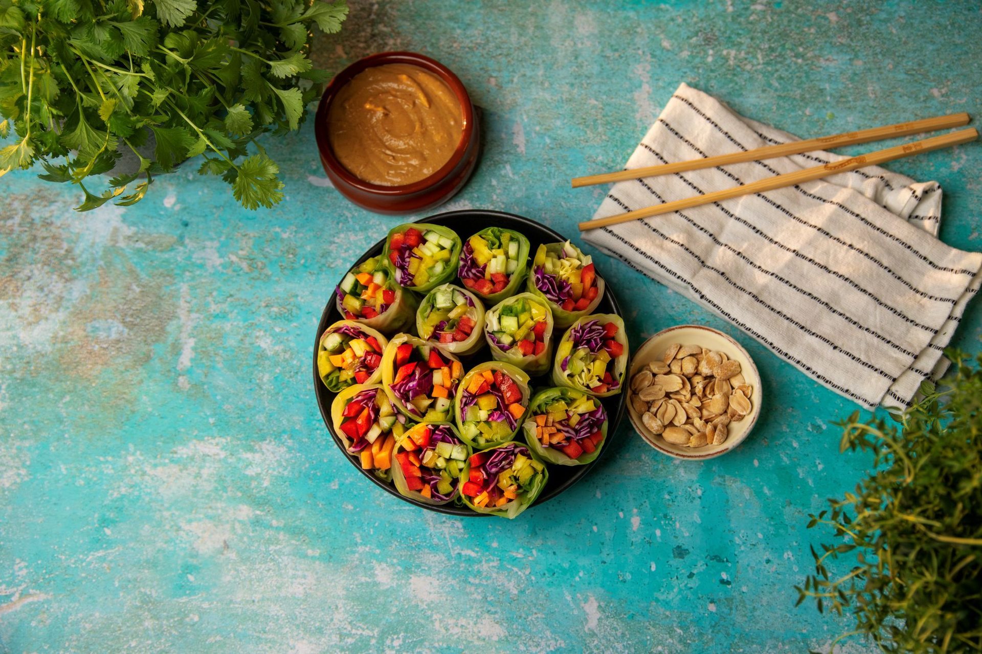 A plate of vibrant spring rolls filled with colorful vegetables, served with peanut sauce and peanuts.