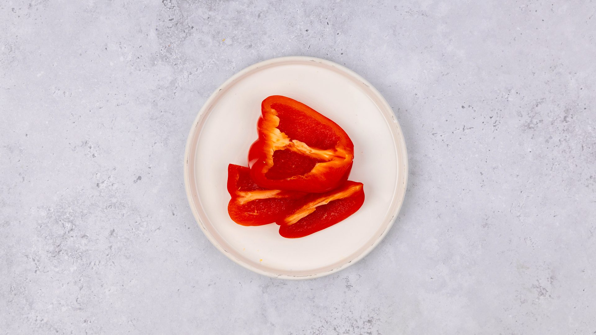 Cut red bell peppers on a white plate.