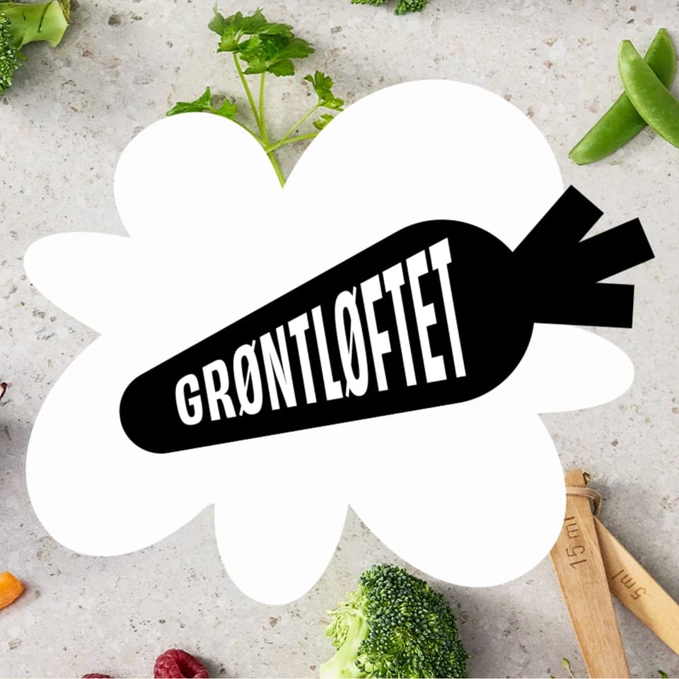 A black carrot logo with 'GRØNTLØFTET' text, on a white cloud shape, surrounded by fresh vegetables.