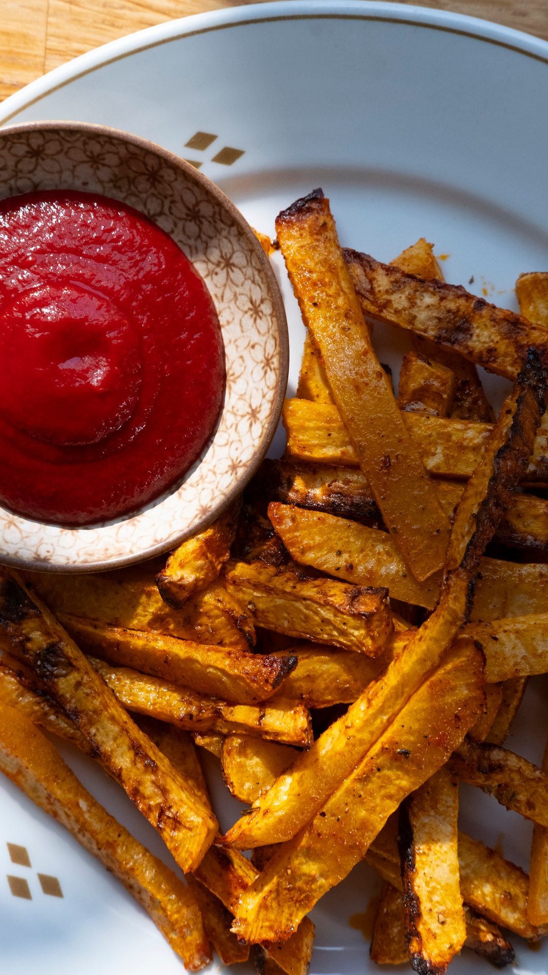 Crispy golden fries served on a white plate with a bowl of vibrant red ketchup.